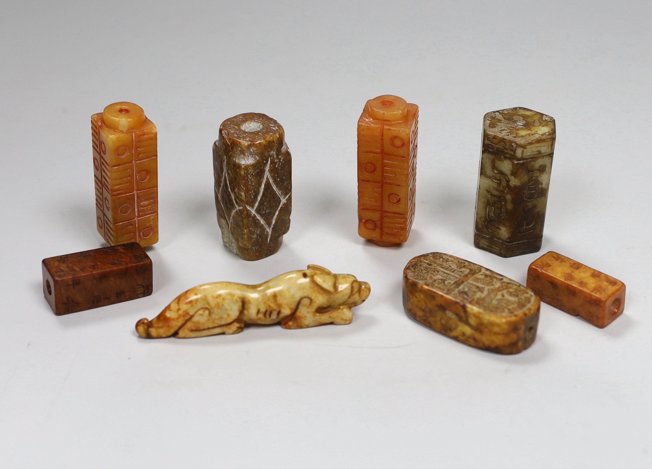 Eight Chinese archaistic jade or hardstone pendants/beads with carved decoration, the largest 9cm wide